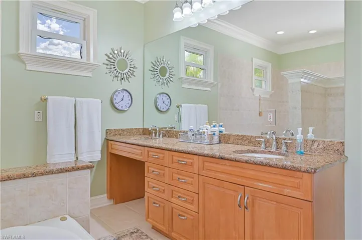 Full bathroom featuring plenty of natural light, double vanity, tile patterned floors, a bath, and crown molding