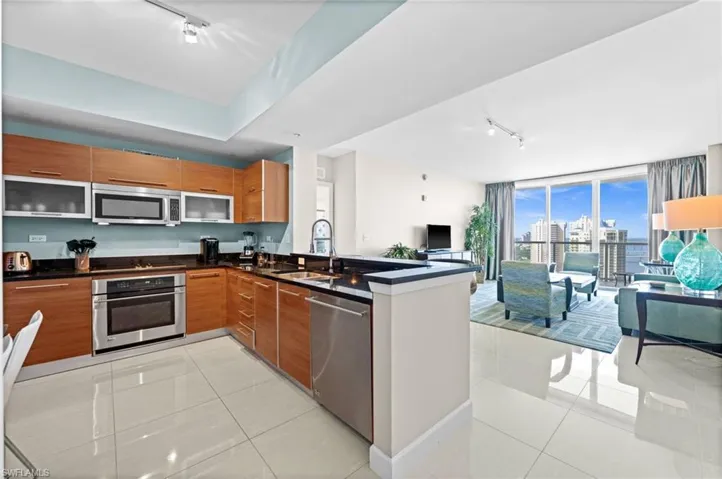Kitchen with track lighting, modern cabinets, light tile patterned flooring, appliances with stainless steel finishes, and expansive windows