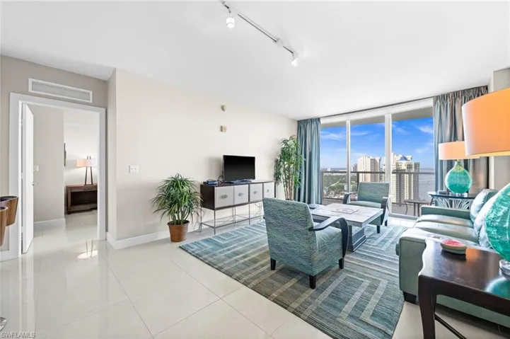 Living area featuring track lighting, light tile patterned floors, and expansive windows