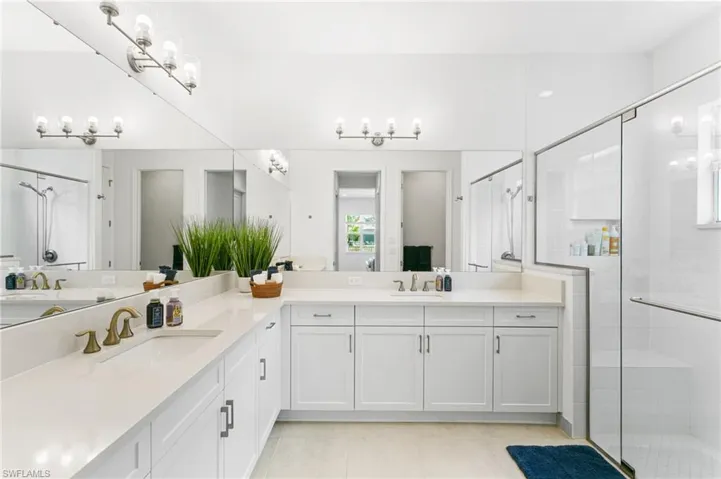Spacious bathroom featuring an extended vanity with two undermount sinks, white cabinetry, and a light-colored countertop