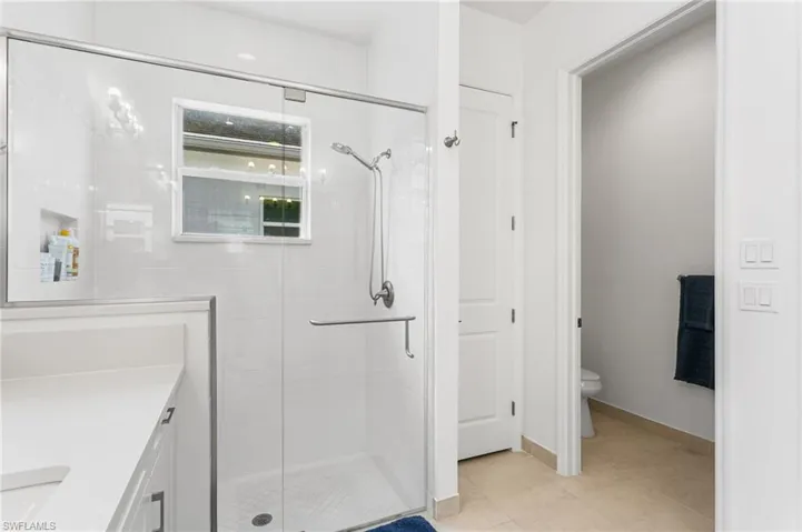 Glass-enclosed shower featuring a built-in niche, window, and chrome fixtures