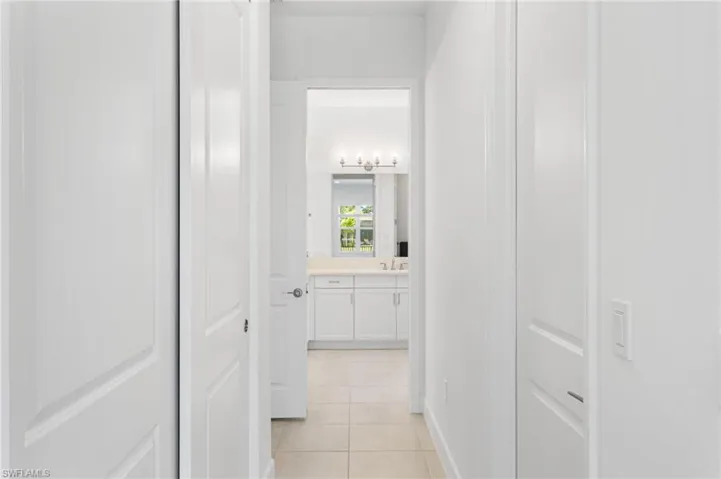 Hallway with light-toned tile flooring and white paneled doors