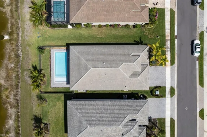 Aerial perspective showcasing the property's exterior, including a swimming pool with integrated steps, a landscaped yard, and a paved driveway