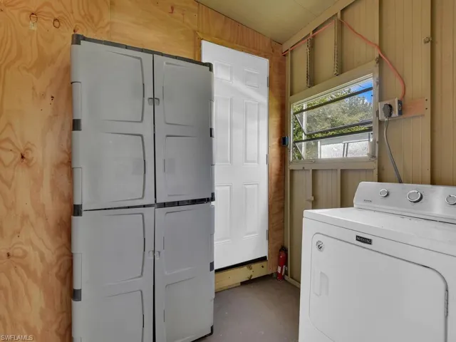 Clothes washing area featuring cabinets, washer / dryer, and wood walls