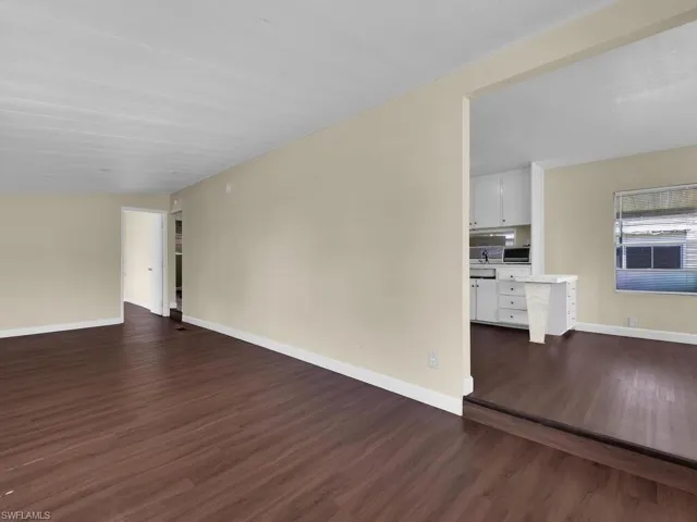 Spare room featuring dark wood-type flooring and vaulted ceiling