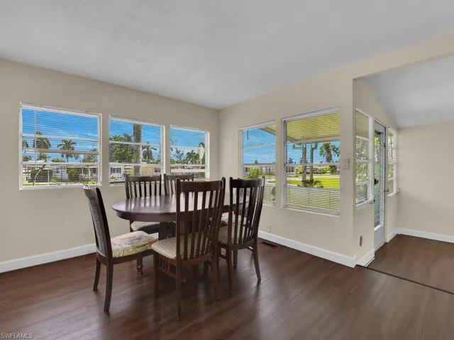 Dining room with dark wood-type flooring, a wealth of natural light, and vaulted ceiling