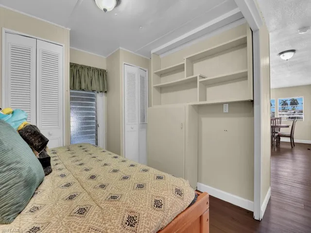 Bedroom featuring a textured ceiling, multiple closets, and dark hardwood / wood-style flooring