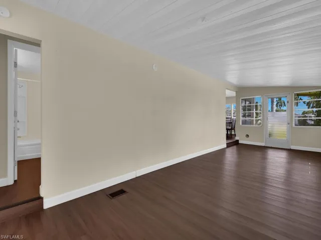 Unfurnished room featuring dark wood-type flooring and vaulted ceiling