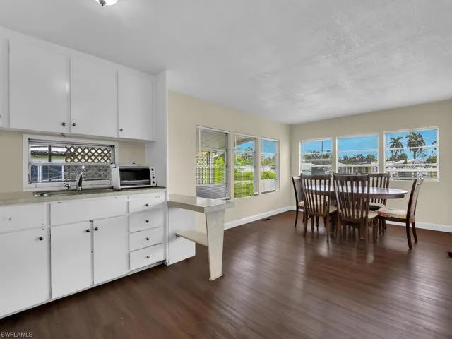 Kitchen featuring white cabinetry, tasteful backsplash, a textured ceiling, sink, and dark wood-type flooring