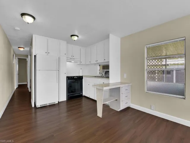 Kitchen featuring white cabinets, white fridge, black range with electric stovetop, and dark hardwood / wood-style flooring