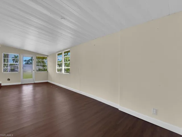 Unfurnished room with dark wood-type flooring and vaulted ceiling