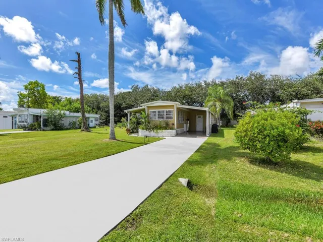 View of front of home with a front yard and a carport