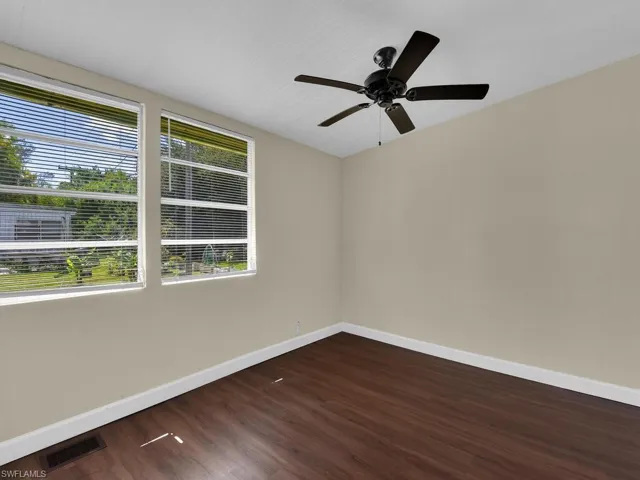 Empty room featuring ceiling fan and dark hardwood / wood-style floors