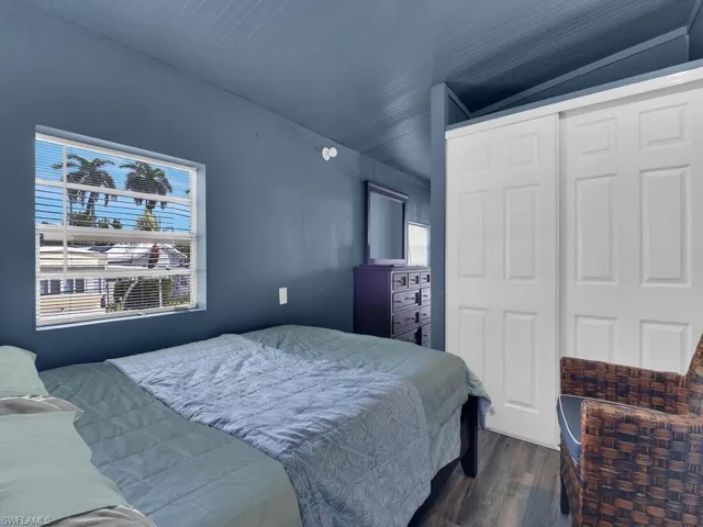 Bedroom featuring dark hardwood / wood-style floors, lofted ceiling, and a closet