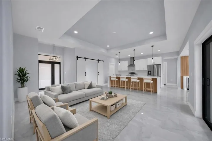 Open-concept living space featuring a spacious kitchen island, stainless steel appliances, recessed lighting, and large format floor tiles