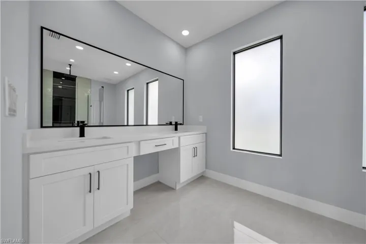 Dual vanity with white cabinetry and integrated sinks, matte black faucets, and an expansive wall-mounted mirror