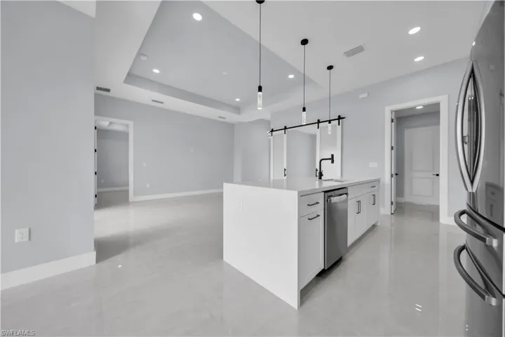 Contemporary kitchen island with a light-toned countertop, integrated sink, matte black faucet, and pendant lighting