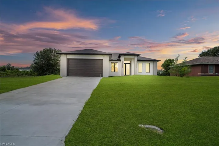Modern exterior architecture with a flat roofline, attached garage, concrete driveway, and expansive lawn