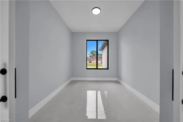 Recessed lighting, large window with black framing, gray tile flooring, and light gray wall finish