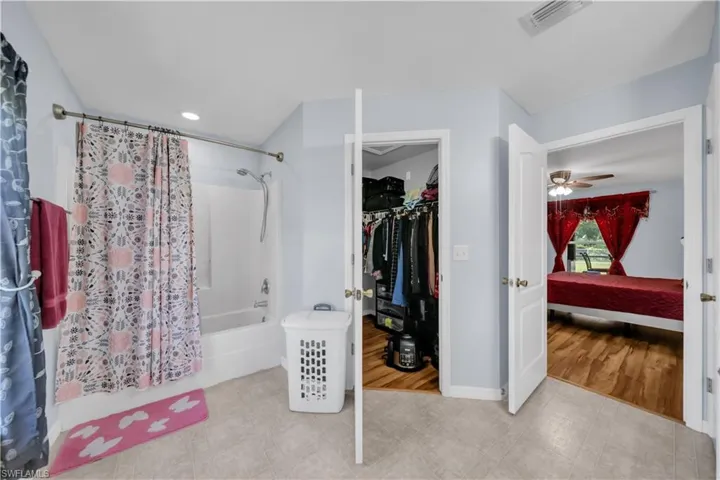 Ensuite bathroom featuring shower / tub combo, a walk in closet, ceiling fan, recessed lighting, and light tile patterned flooring