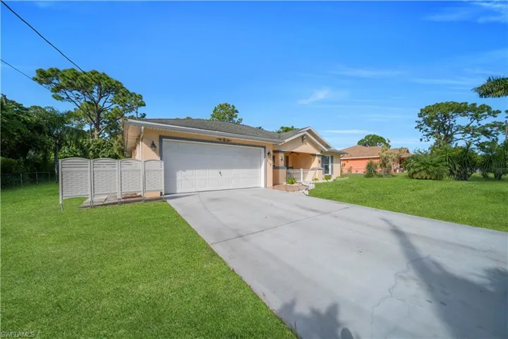 Ranch-style house featuring driveway, an attached garage, stucco siding, and a gate