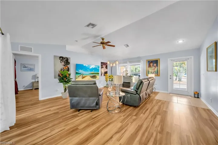 Living area with a ceiling fan, light wood finished floors, lofted ceiling, and a chandelier