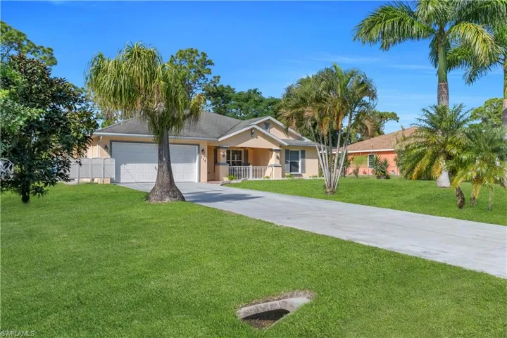 Ranch-style home with driveway, a front yard, an attached garage, and stucco siding