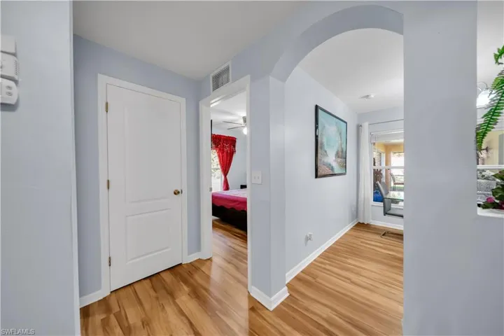 Hallway featuring arched walkways and light wood-style flooring