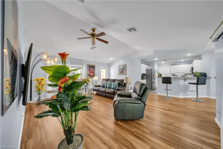 Living room with vaulted ceiling, light wood-style flooring, ceiling fan, and recessed lighting