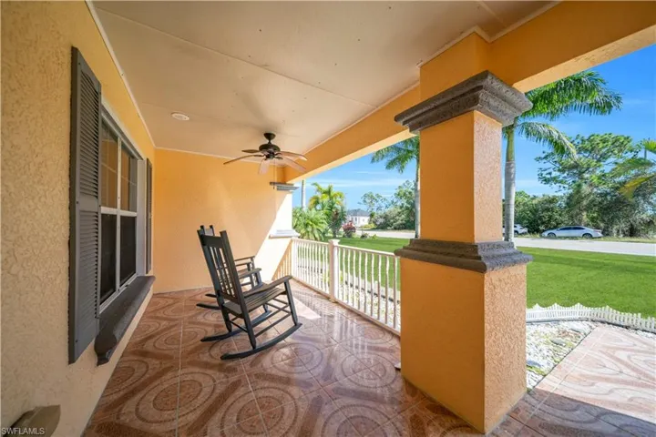 Covered porch featuring a ceiling fan and a lawn