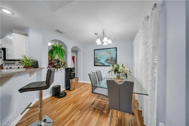 Dining space featuring arched walkways, light wood finished floors, and a chandelier