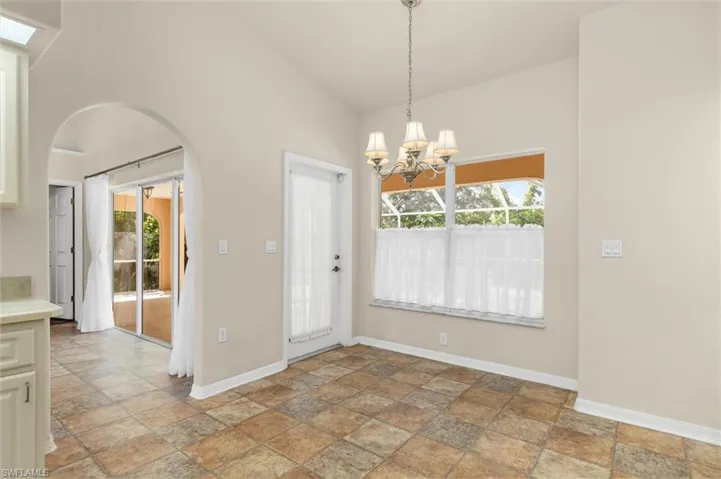 Unfurnished dining area featuring high vaulted ceiling, a chandelier, and vinyl patterned flooring