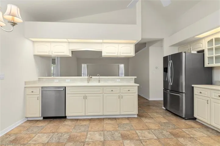 Kitchen with kitchen peninsula, sink, vaulted ceiling, appliances with stainless steel finishes, and light patterned floors