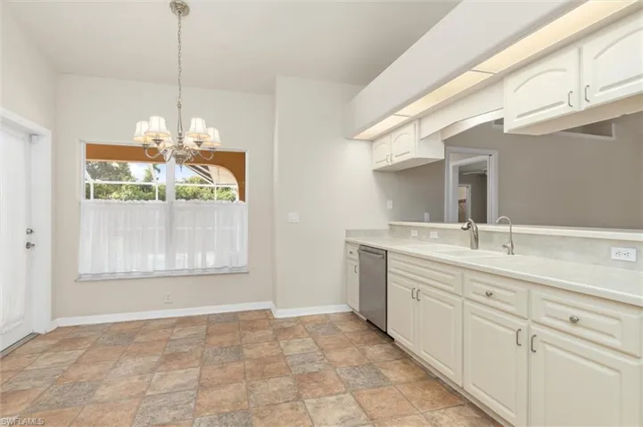 Kitchen featuring an inviting chandelier, sink, decorative light fixtures, light vinyl patterned floors, and dishwasher
