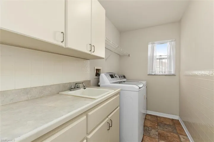 Laundry area with washer and dryer, sink, tile walls vinyl patterned flooring, and cabinets