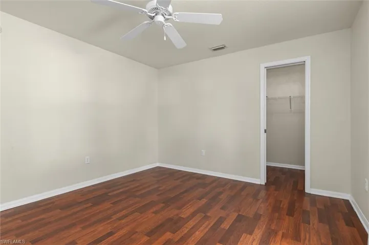 Unfurnished bedroom featuring a spacious closet, wood-style floors, ceiling fan, and a closet