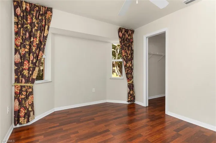 Unfurnished bedroom with dark hardwood / wood-style flooring, a walk in closet, ceiling fan, and a closet