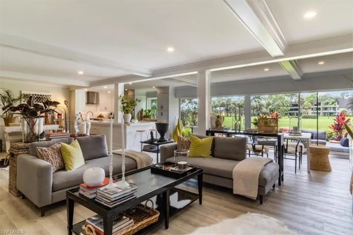 Living room with crown molding, light wood-type flooring, and beam ceiling
