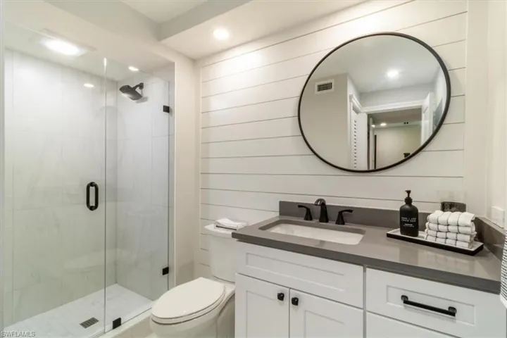 Bathroom featuring walk in shower, toilet, and vanity