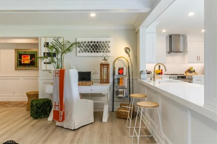 Dining room with ornamental molding, sink, light wood-type flooring, and beamed ceiling