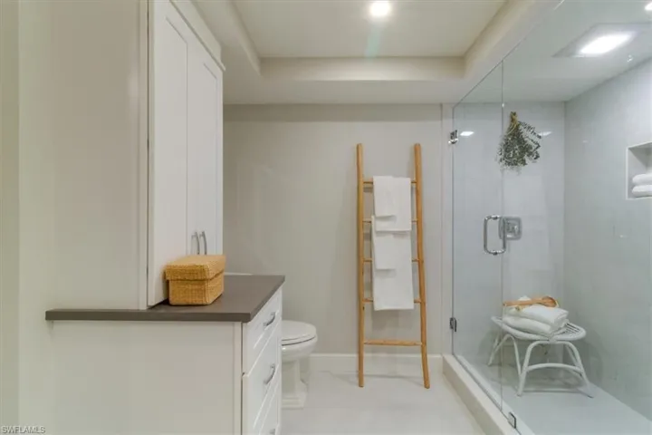 Bathroom featuring toilet, a shower with door, and vanity