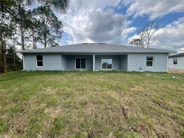 Rear view of house featuring stucco siding and a lawn