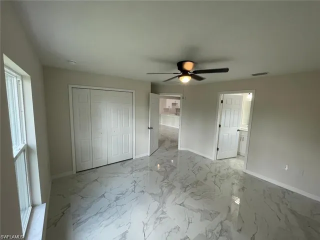 Unfurnished bedroom with baseboards, a closet, marble finish flooring, and ceiling fan