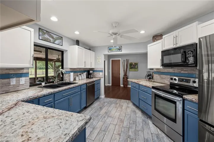 Kitchen with stainless steel appliances, tile plank flooring recessed lighting