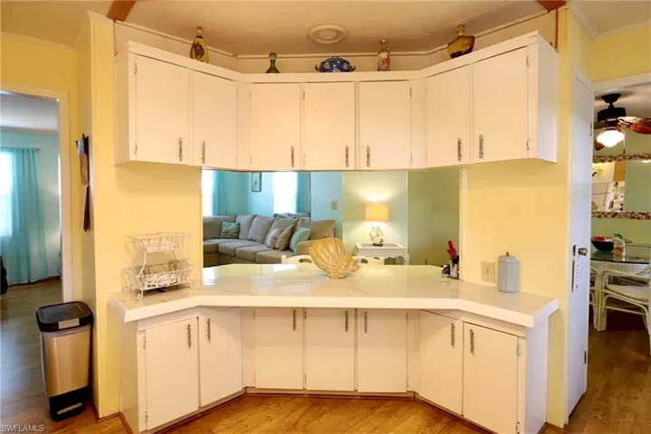 Kitchen with crown molding, hardwood / wood-style flooring, white cabinets, and ceiling fan