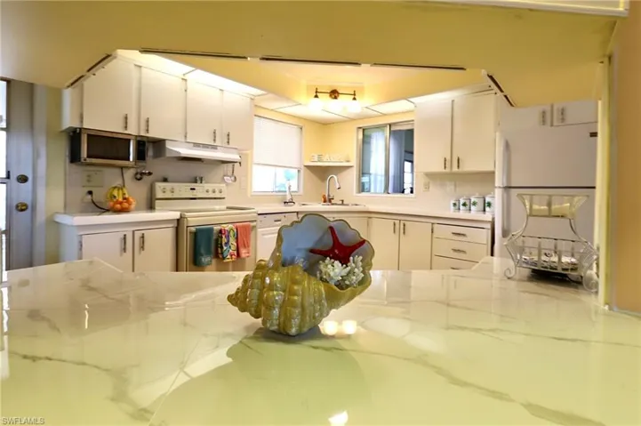Kitchen with sink, white cabinetry, white appliances, and a tray ceiling