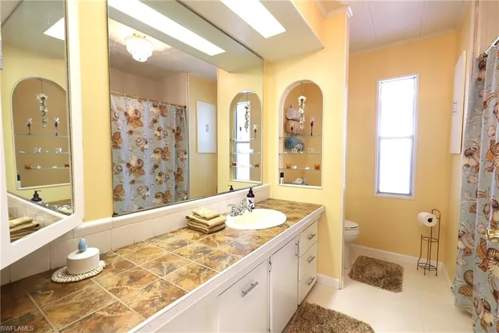 Bathroom with tile floors, crown molding, toilet, and vanity with extensive cabinet space