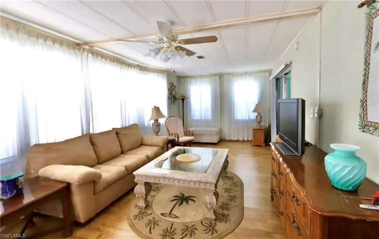 Living room featuring a healthy amount of sunlight, light wood-type flooring, and ceiling fan