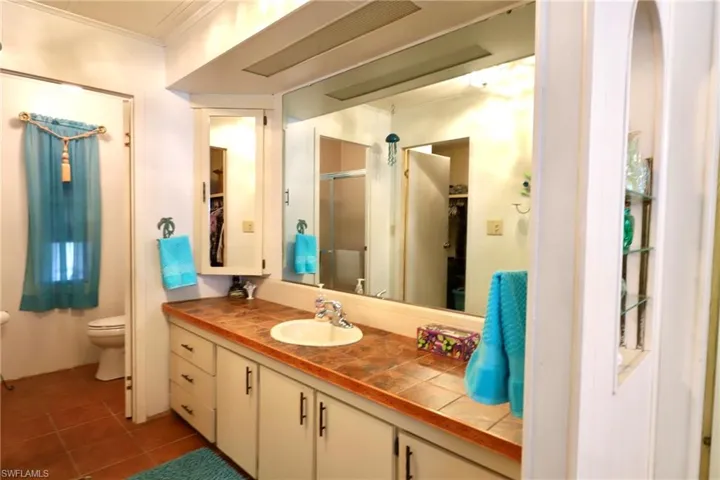 Bathroom with ornamental molding, tile flooring, toilet, and large vanity