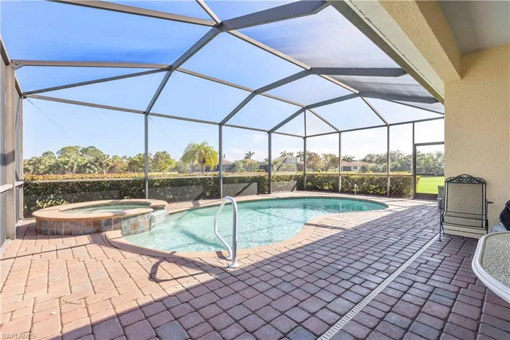 View of pool with an in ground hot tub, glass enclosure, and a patio area